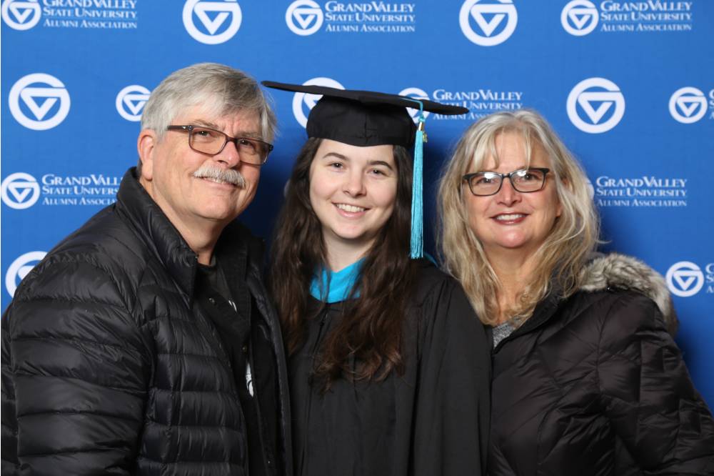 A future graduate and her parents smile for a photo together at Gradfest